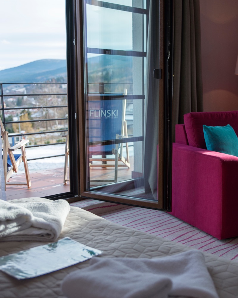 Apartament z balkonem: szlafrok na łóżku, za oknem góry