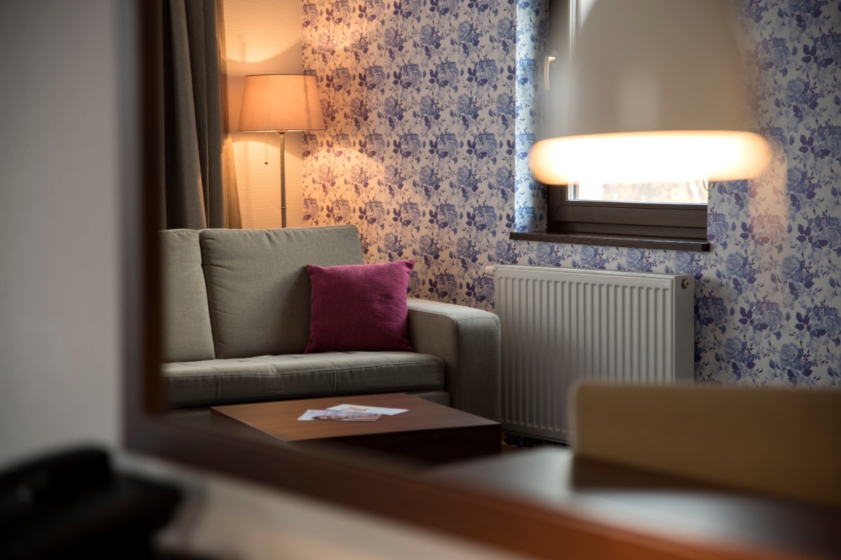 Kącik wypoczynkowy w apartamencie: sofa, lampa i tapeta w kwiaty
